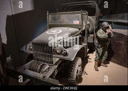 Soldat en Normandie criant pour des renforts à la radio, il est équipé d'une mitrailleuse Thompson et à côté d'un GMC turck Banque D'Images