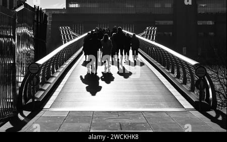 Piétons silhouettés traversant la passerelle du millénaire sur la Tamise, Londres, Angleterre, Royaume-Uni . Banque D'Images