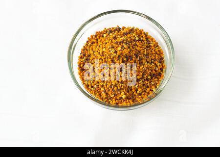 Granules de pollen d'abeille dans un bol en verre sur fond blanc.Superfood, mélange de nectar de fleur, enzymes, miel, sécrétions de cire. Nutriments, acides aminés, l Banque D'Images