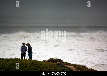 Deux hommes regardent d'énormes vagues de tempête hivernale au large des côtes de Californie Banque D'Images