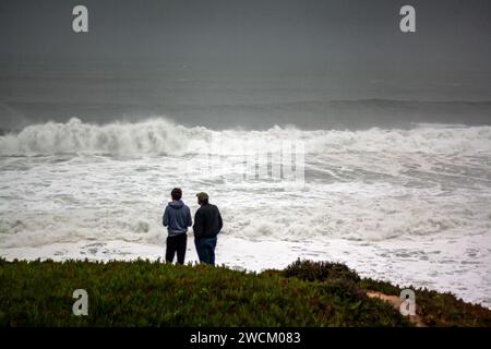 Deux hommes regardent d'énormes vagues de tempête hivernale au large des côtes de Californie Banque D'Images