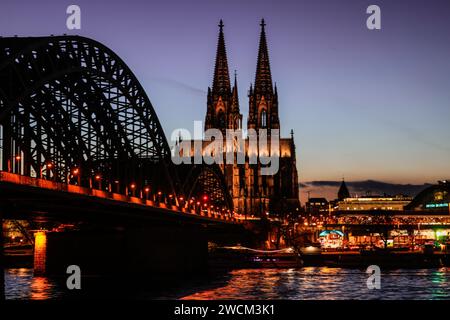 Cologne, Allemagne. 16 janvier 2024. La cathédrale et le pont Hohenzollern sont illuminés le soir. Crédit : Oliver Berg/dpa/Alamy Live News Banque D'Images