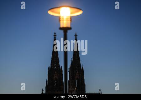 Cologne, Allemagne. 16 janvier 2024. Une lanterne brille sur les tours de la cathédrale le soir. Crédit : Oliver Berg/dpa/Alamy Live News Banque D'Images