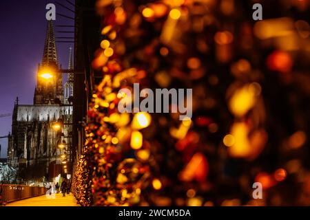 Cologne, Allemagne. 16 janvier 2024. Les écluses d'amour s'allument le soir sur le pont Hohenzollern en face de la cathédrale. Crédit : Oliver Berg/dpa/Alamy Live News Banque D'Images