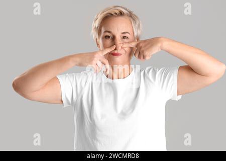 Femme mature faisant un exercice de construction de visage sur fond clair Banque D'Images