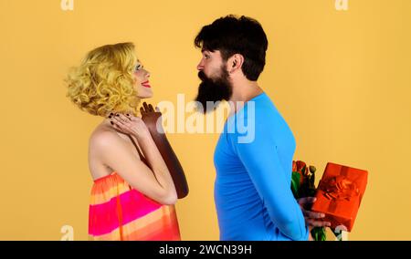Saint Valentin, fête des femmes ou de la fête des mères. Homme barbu avec bouquet de tulipes et coffret cadeau pour sa petite amie. Amour romantique Banque D'Images