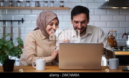 Marié couple heureux utiliser ordinateur portable lire les nouvelles en ligne reçu grand e-mail cri avec joie célébrant l'occasion à la maison dans la cuisine Banque D'Images