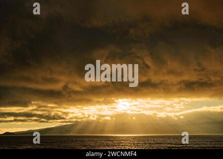 Coucher de soleil spectaculaire avec des rayons du soleil traversant les nuages sur la mer, Criacao Velha, île de Pico, Açores, Portugal Banque D'Images