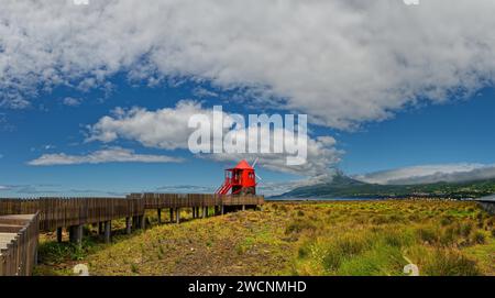 Chemin en bois mène au moulin à vent Moinho das Lajes avec un ciel spectaculaire et le cône volcanique de Pico en arrière-plan, village de pêcheurs, Lajes Do Banque D'Images