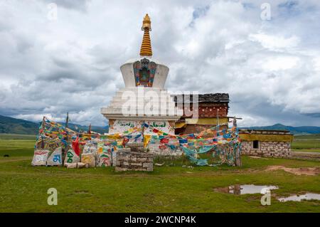 Tibet, Kham, Litang. Des drapeaux de prière entourent un stupa bouddhiste sur le plateau tibétain. Banque D'Images