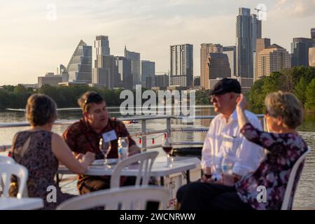 Un groupe de personnes dégustant un repas au bord de la rivière avec pour toile de fond la ville Banque D'Images