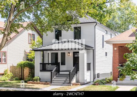 Une maison magnifiquement rénovée avec revêtement blanc et accents noirs et un porche couvert. Banque D'Images