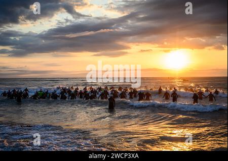 Triathlètes en combinaison courant dans la mer pendant un beau lever de soleil pour commencer la compétition à Burriana, Castellon, Espagne Banque D'Images