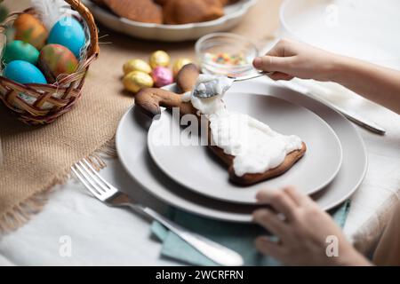 Childs mains décorant le biscuit en forme de lapin de Pâques avec cerise sur la table décorée festive Banque D'Images