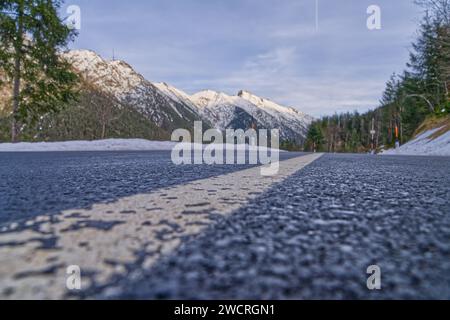 Une route de montagne pittoresque s'étendant à travers un paysage enveloppé dans un ciel blanc serein Banque D'Images