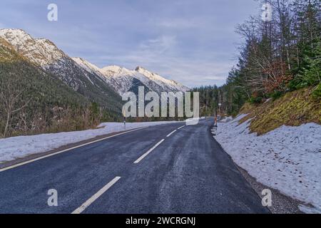Une route de montagne enneigée, mettant en valeur la sérénité et la beauté des paysages hivernaux Banque D'Images
