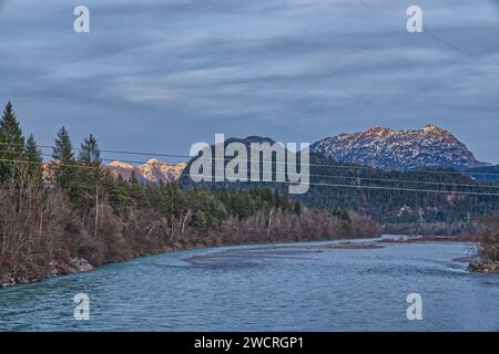 Une rivière sereine qui coule à travers une forêt luxuriante entourée de montagnes majestueuses Banque D'Images