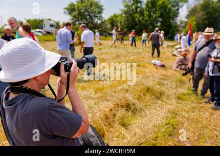 Une photographe âgée avec un chapeau blanc prend la photo de deux photographes ensemble avant que les agriculteurs ne commencent à récolter le grain manuellement en rur traditionnel Banque D'Images