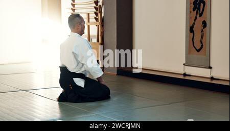 Homme asiatique, sensei et arc dans le dojo pour l'honneur, le salut ou le respect du maître à la salle de gym intérieure. Personne masculine ou entraîneur de karaté s'inclinant en classe pour l'étiquette Banque D'Images