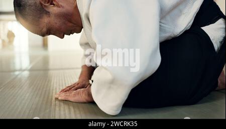 Homme asiatique, étudiant ou arc dans le dojo pour le respect, le salut ou l'honneur à maîtriser à la salle de gym intérieure. Gros plan d'une personne masculine ou d'un entraîneur de karaté qui s'incline Banque D'Images