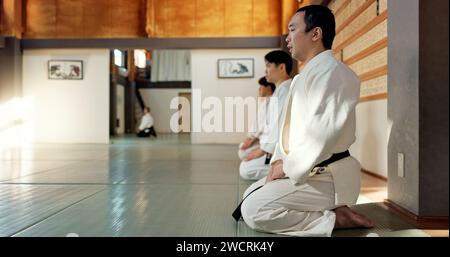 Homme asiatique, classe et arc dans le dojo pour le respect, le salut ou l'honneur à maîtriser à la salle de gym intérieure. Personne masculine ou groupe en karaté s'inclinant sur le sol pour l'étiquette Banque D'Images