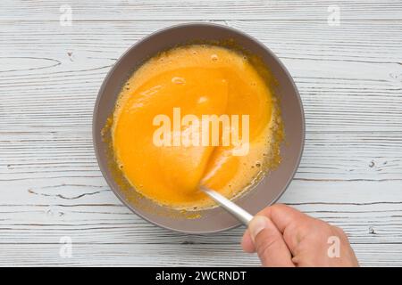 Assiette de jaune d'oeuf fouetté avec du sucre en préparation pour la crème sucrée Banque D'Images