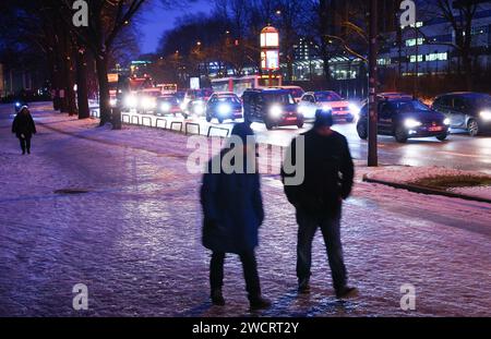 Hambourg, Allemagne. 17 janvier 2024. Les piétons marchent sur un vélo glacé et un sentier pédestre à côté d'une route principale dans des conditions hivernales dans le centre-ville. La neige et la glace noire obstruent la circulation dans de nombreuses régions d'Allemagne. Crédit : Christian Charisius/dpa/Alamy Live News Banque D'Images