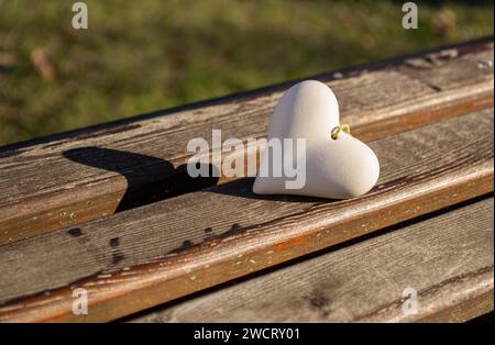 Un coeur en pierre repose sur un banc en bois Banque D'Images