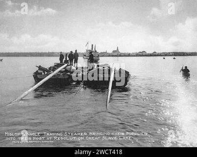 Une photographie de 1901 de fournitures transportées par bateau à vapeur et chaloupe à fort Resolution (vue en arrière-plan) sur le Grand lac des esclaves dans les Territoires du Nord-Ouest, prise par C W Mathers lors d’une expédition dans le Grand Nord du Canada et publiée dans son livre « The Far North ». Mathers a sous-titré cette photo : le bateau à vapeur Hislop & Nagle, amenant leurs fournitures à leur poste à Resolution, Grand lac des esclaves. Banque D'Images