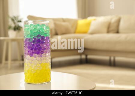 Différentes couleurs de remplissage dans le vase en verre sur la table blanche à la maison, espace pour le texte. Perles d'eau Banque D'Images