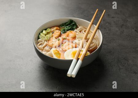 Délicieux ramen avec crevettes et baguettes sur la table grise. Soupe de nouilles Banque D'Images