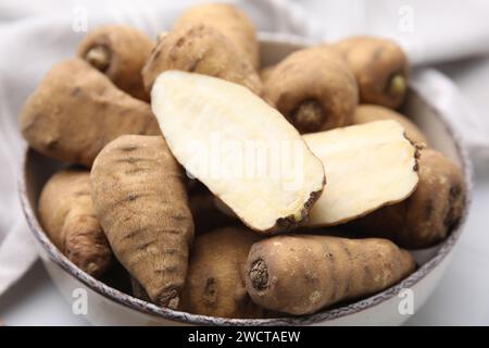 Tubercules entiers et coupés de cerfeuil enraciné dans un bol sur la table, gros plan Banque D'Images