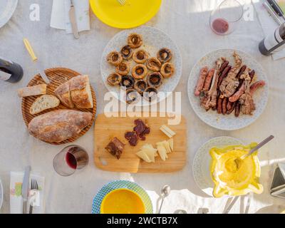 Plat de table servi avec des assiettes de champignons hot-dog sauce viande grillée tranches de bouteilles de pain et tasses de boissons et cuillères à fourchette et couteaux Banque D'Images