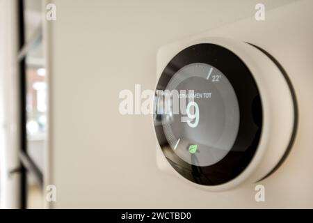 Image rapprochée d'un thermostat numérique intelligent monté sur un mur, montrant un réglage de température avec un arrière-plan flou. Banque D'Images