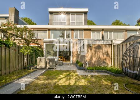 Une maison moderne de deux étages arborant des lignes épurées et un jardin spacieux avec un patio, parfait pour la détente et la vie en plein air. Banque D'Images