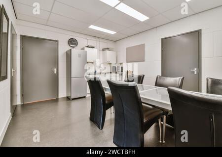 Salle de repos de bureau contemporaine avec kitchenette élégante, table à manger avec chaises et design minimaliste. Banque D'Images