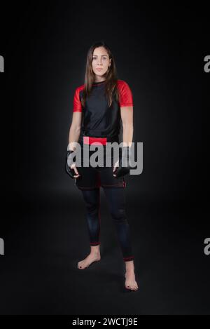 La combattante féminine MMA est présentée dans une pose qui reflète non seulement ses prouesses physiques, mais aussi sa concentration intense et son dévouement. Sa determine Banque D'Images