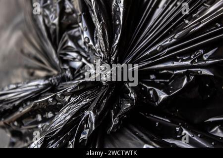 GOIANIA GOIAS BRÉSIL - 14 JANVIER 2024 : détail d'un noeud dans un sac en plastique noir avec des ordures, mouillé, avec des gouttes d'eau de pluie. Banque D'Images