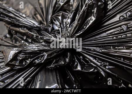 GOIANIA GOIAS BRÉSIL - 14 JANVIER 2024 : détail d'un noeud dans un sac en plastique noir avec des ordures, mouillé, avec des gouttes d'eau de pluie. Banque D'Images