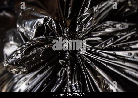 GOIANIA GOIAS BRÉSIL - 14 JANVIER 2024 : détail d'un noeud dans un sac en plastique noir avec des ordures, mouillé, avec des gouttes d'eau de pluie. Banque D'Images