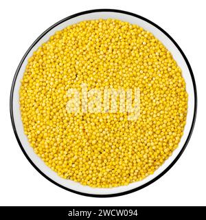 Vue de dessus des grains de millet jaune crus dans un bol isolé sur fond blanc Banque D'Images
