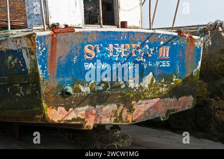 Bateau de pêche abandonné attaché au mur du port à Beadnell sur la côte du Northumberland en mars. Nommé St Ebbs Third et Farne Boating Services Banque D'Images