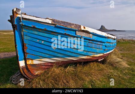 Vue du bateau abandonné, traîné sur l'herbe sur Lindisfarne toujours avec le château de Lindisfarne au loin sur la côte Northumberlands Banque D'Images
