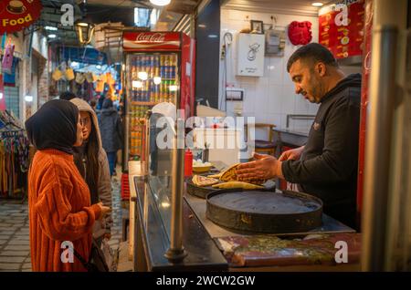 Deux femmes s’arrêtent pour acheter du Brik, une collation savoureuse, dans une boutique à l’intérieur du souk de la médina de Sousse, en Tunisie. La médina est classée au patrimoine mondial de l'UNESCO Banque D'Images