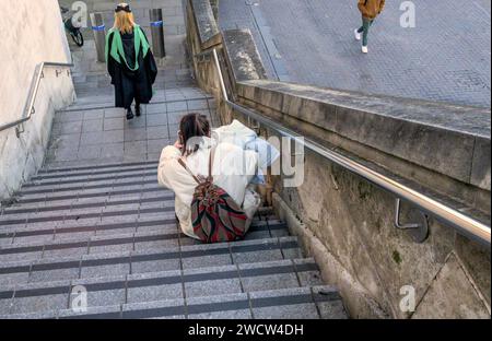 Londres, Royaume-Uni. Des gens sur des marches sur la rive sud. Fille orientale en robe de graduation et une autre assise sur une marche Banque D'Images