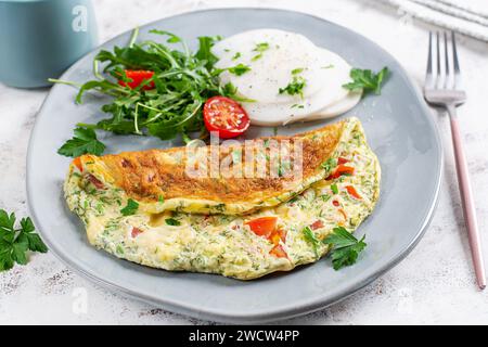 Omelette avec tomates et salade sur assiette. Frittata - omelette italienne. Céto, régime cétogène. Banque D'Images