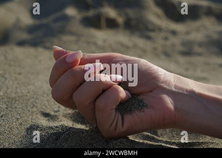 Gros plan de la main d'une femme libérant du sable tombant. Banque D'Images