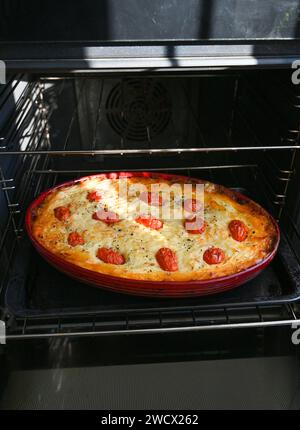 Home Cooking un Cottage Pie fait avec de la viande hachée de bœuf et garni de purée de pommes de terre avec des poireaux, du fromage et de petites tomates Banque D'Images