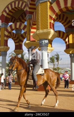 Espagne, Andalousie, Cordoue, cavalier en costume traditionnel à cheval devant la porte d'entrée monumentale jaune et rouge de la feria de Nuestra Señora de la salud Banque D'Images