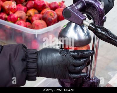 Faire du jus de grenade avec une presse à main Banque D'Images